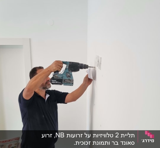 אדם קודח בקיר עם מקדחה חשמלית